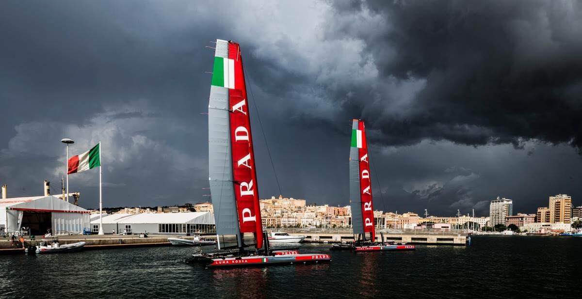 Luna Rossa wing-sail catamarans moored beneath a storm sky